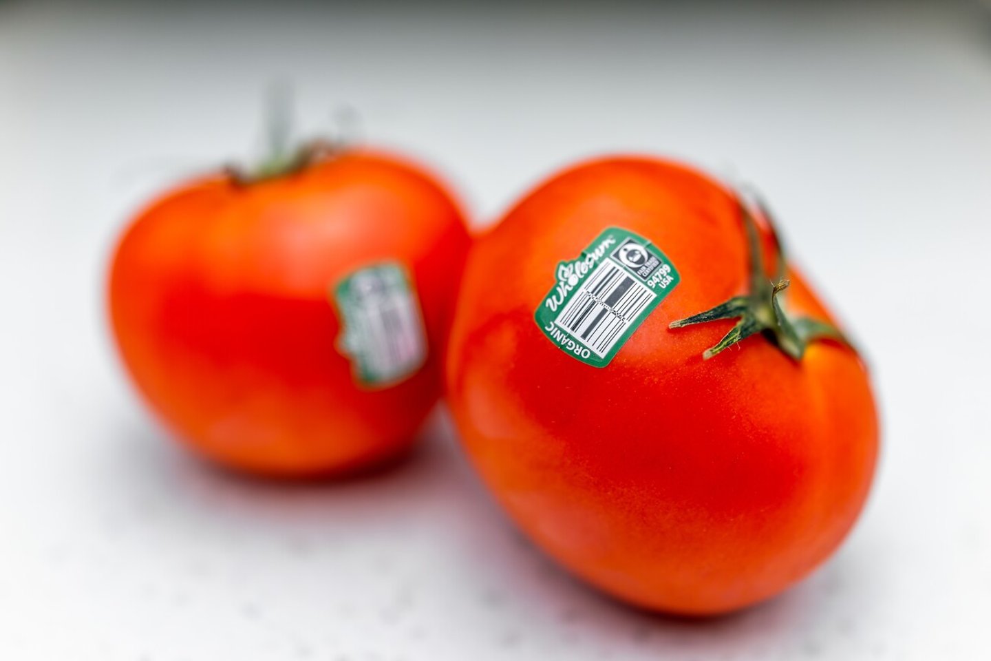 Naples, USA - January 26, 2022: Raw red vine tomatoes fruit vegetables macro closeup with two pieces and stickers for organic fair trade certified by Wholesum brand; Shutterstock ID 2263627703