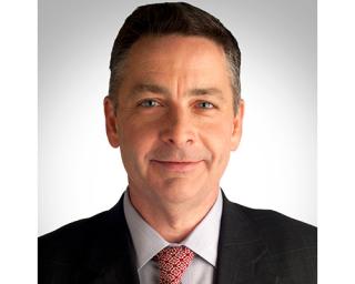 a man wearing a suit and tie smiling at the camera